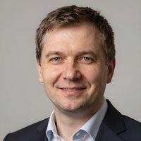 Портрет уверенного российского бизнесмена с дружелюбным взглядом на нейтральном размытом фоне студии