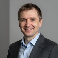 Портрет уверенного российского бизнесмена с дружелюбным взглядом на размытом нейтральном фоне в студии